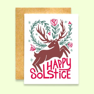 May include: A white card with a red deer with large antlers surrounded by green leaves and red flowers. The text "HAPPY SOLSTICE" is written in red and white.