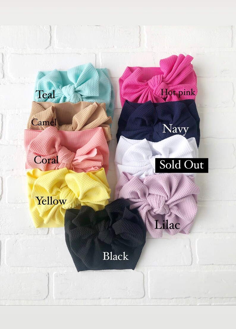 May include: Assortment of fabric headbands in various colors, including teal, camel, coral, yellow, black, lilac, hot pink, navy, and white. Some headbands are sold out.