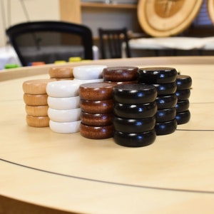 May include: A set of wooden draughts pieces in brown, white and black. The pieces are stacked in piles on a wooden game board.