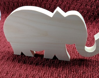 May include: A wooden elephant cutout, unpainted, with a smooth surface. The elephant is standing on a red textured surface.