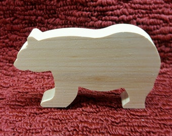 May include: A wooden bear figurine, cut from light-colored wood, stands in profile against a textured, burgundy background. The bear has a simple, stylized design, with visible wood grain. This decorative item could be used as a toy or home decor.