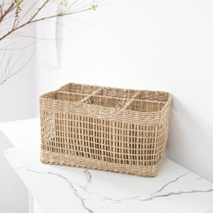 Może przedstawiać: Naturalny wiklinowy kosz z sześcioma przegródkami. Kosz jest prostokątny i ma jasnobrązowy kolor.