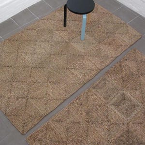 May include: Two brown woven rugs with a diamond pattern. The rugs are made of natural fibers and have a rustic look.