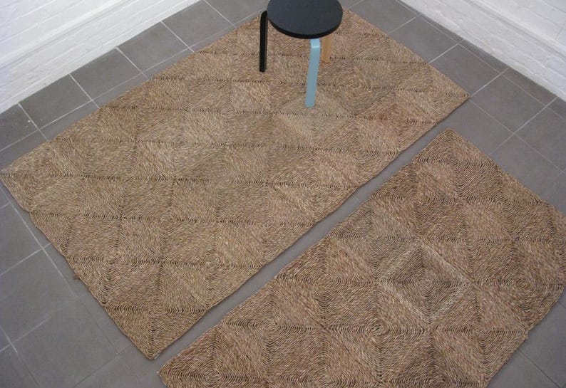 May include: Two brown woven rugs with a diamond pattern. The rugs are made of natural fibers and have a rustic look.