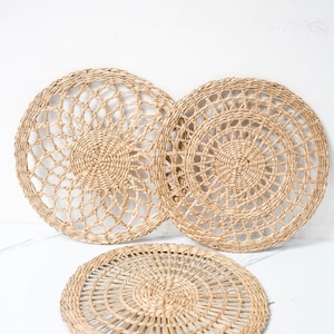 Peut inclure: Trois sets de table ronds en paille tressée avec un motif décoratif. Les sets de table sont faits de matériaux naturels et ont une couleur brun clair.