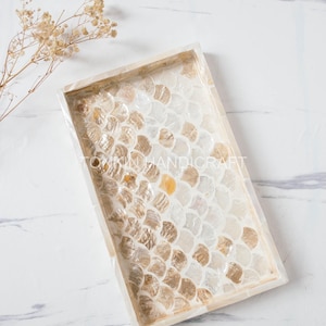 May include: A rectangular tray featuring a decorative inlay of iridescent, scale-shaped shell pieces in shades of white, cream, and gold. The tray has a smooth, light-colored border and the text TONKIN HANDICRAFT is visible in the center.