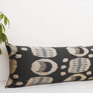 May include: A long black and white patterned pillow with a geometric design. The pillow is made of a soft, textured fabric.