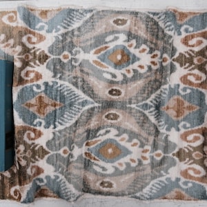 Pode incluir: Um tapete com padrão azul e marrom com um livro azul em cima. O livro tem o texto "Andy Warhol" escrito em letras douradas.