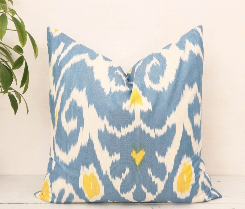 May include: A blue and white throw pillow with a yellow ikat pattern.