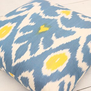May include: A blue and white throw pillow with a yellow ikat pattern.
