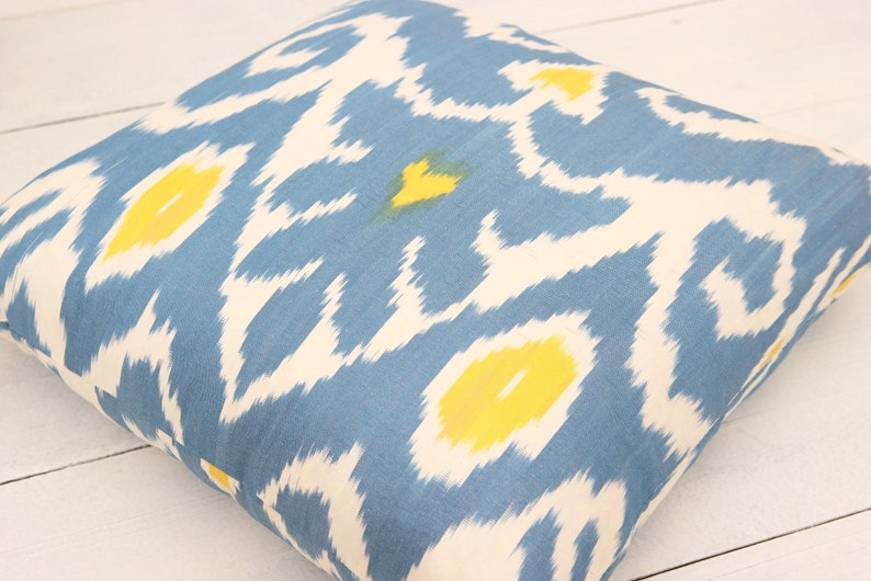 May include: A blue and white throw pillow with a yellow ikat pattern.