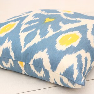 May include: A blue and white throw pillow with a yellow ikat pattern.
