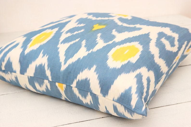 May include: A blue and white throw pillow with a yellow ikat pattern.