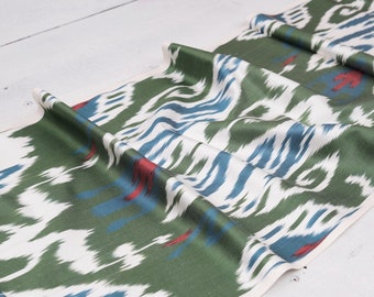 May include: Green, white, and blue ikat fabric with a repeating pattern. The fabric is folded and has a white border.