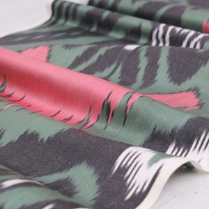 May include: Green, black, and pink patterned fabric with a white border. The fabric has a soft, silky texture.