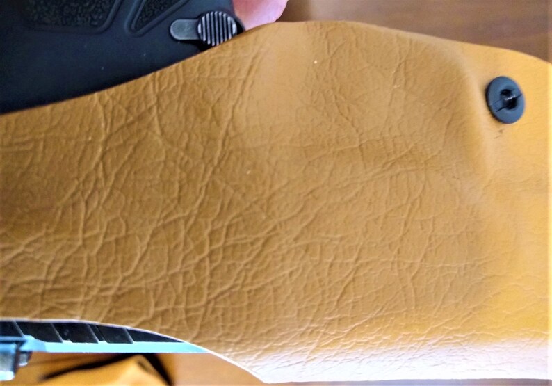 K&ouml;nnte beinhalten: Ein braunes Lederholster mit einem schwarzen Druckknopfverschluss.