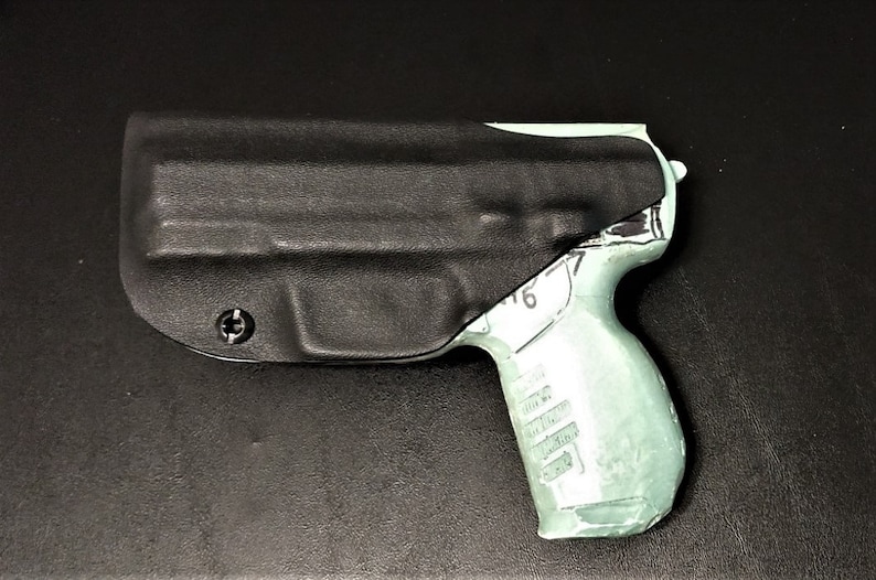 May include: A black leather holster with a screw on the side, holding a light green plastic gun.