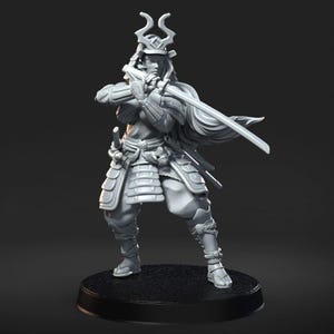 May include: A gray, detailed miniature figurine of a samurai warrior in full armor, holding a sword and standing on a round base.