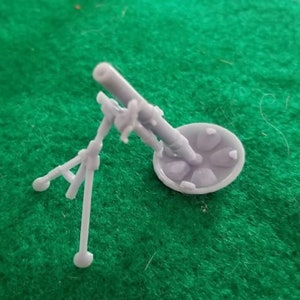 May include: A grey plastic model of a mortar with a base and a tripod stand.