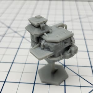 May include: A gray 3D printed model of a futuristic building with a hexagonal base. The building has a layered design with a flat roof and a small tower on top.