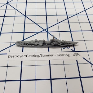 May include: A grey model of a Gearing class destroyer, a type of US Navy warship. The model is labelled "Destroyer: Gearing/Summer - Gearing - USN".