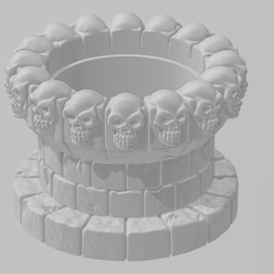 May include: A white ceramic planter with a circular opening at the top, surrounded by a ring of skulls. The planter is sitting on a base made of stacked stone blocks.