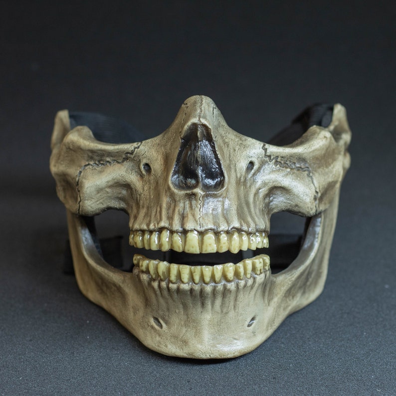 Pu&ograve; includere: Una maschera a teschio dettagliata, a mezza faccia, con finitura color osso invecchiata. La maschera presenta dettagli realistici dei denti e della cavit&agrave; nasale, con un cinturino nero per fissarla. Progettata per costumi o decorazioni.