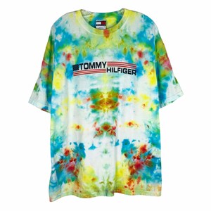 May include: A tie-dye t-shirt with a blue, yellow, red, and white color scheme. The shirt features a Tommy Hilfiger logo with an American flag design.