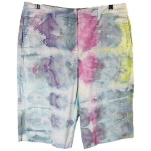 May include: Tie-dye shorts in a light blue base with pink, purple, and yellow accents. The shorts have a classic cut and a relaxed fit.