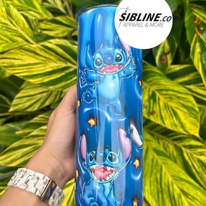 Może przedstawiać: Niebieski kubek ze stali nierdzewnej z wzorem Stitch z Lilo & Stitch. Kubek ma niebieskie tło z białymi gwiazdami, a Stitch jest przedstawiony w r&oacute;żnych pozach. Na kubku nadrukowany jest tekst "Sibline.co Apparel & More".