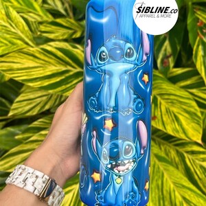 Może przedstawiać: Niebieski kubek ze stali nierdzewnej z powtarzającym się wzorem Stitch, niebieskiego kosmity z filmu Disneya Lilo & Stitch. Kubek ma biały wz&oacute;r gwiazdy i tekst "SIBLINE.CO Apparel & More".