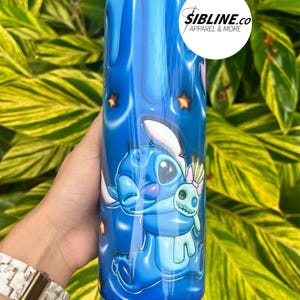 Może przedstawiać: Niebieski kubek ze stali nierdzewnej z grafiką przedstawiającą Stitch'a z Lilo & Stitch trzymającego Angel. Kubek ma niebieski, biały i r&oacute;żowy wz&oacute;r z gwiazdami.
