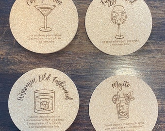 May include: Four round cork coasters with engraved cocktail recipes. The coasters feature recipes for a Cosmopolitan, Fuzzy Navel, Wisconsin Old Fashioned, and Mojito. Each coaster includes a cocktail illustration and ingredient list.