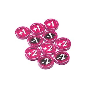 May include: A collection of ten circular game tokens in a vibrant magenta color with a dark starburst pattern. Each token features a white numerical value printed in the center, including positive and negative integers such as +1, -1, +2, and -2.
