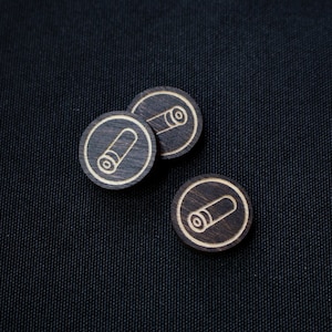 Peut inclure: Trois jetons de jeu en bois avec un motif de balle. Les jetons sont brun foncé avec un contour brun clair d'une balle.