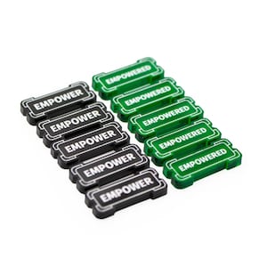 May include: Ten rectangular plastic tokens arranged in two parallel rows. The five black tokens are embossed with the word EMPOWER in white, while the five green tokens are embossed with the word EMPOWERED in white, all featuring a border design.