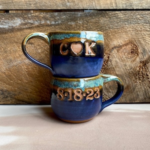 multicolored mugs.  C (heart stamp) K on front of mug and date on opposite side.  Cobalt (primary), mocha inside and ocean rim