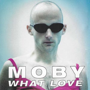 May include: A black and white photo of a person wearing sunglasses and a pink top with the text "MOBY WHAT LOVE" printed on it.