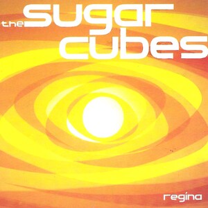 May include: Album cover for "The Sugarcubes" featuring the band's name in large white block letters. The background has a swirling pattern of yellow, orange, and red hues, with a bright white circle in the center. The word "regina" is in the bottom right corner.