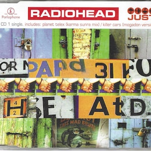 May include: CD single cover for Radiohead's "Just." The cover features a collage of images, including wooden doors, hands, and text fragments. The band's name is in red, and the title "JUST" is in white with four black umbrellas.