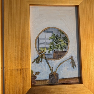 May include: A framed painting of a plant with a circular window reflection in the background. The painting is in a gold frame with a white mount.