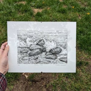 May include: A black and white pen and ink drawing of crashing waves and rocks. The drawing is titled "Crashing Waves" and signed "Madeline Jacobsen".