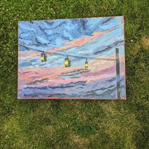 May include: A painting depicting a sunset with a line of streetlights featuring yellow lights strung on a wire. The sky is a blend of blue, pink, and purple.