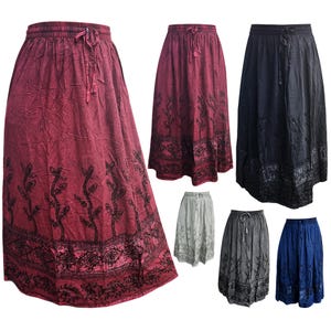 May include: A collection of flowing skirts in various colors, including burgundy, navy, gray, and blue. Each skirt features an elastic waistband with a drawstring and a detailed floral pattern along the hemline and lower portion of the skirt.