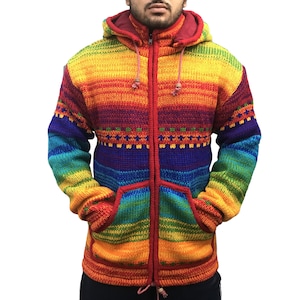Peut inclure: Un sweat à capuche zippé aux couleurs de l'arc-en-ciel. Le pull a une fermeture éclair rouge, une capuche doublée de rouge et deux poches avant. Le motif tricoté comprend des rayures horizontales et une bande à motifs sur la poitrine. Le pull est en matière épaisse et chaude.
