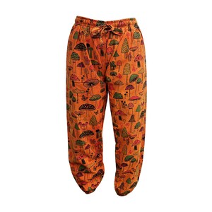 May include: Orange trousers with a mushroom print. The trousers have an elastic waistband and a drawstring.