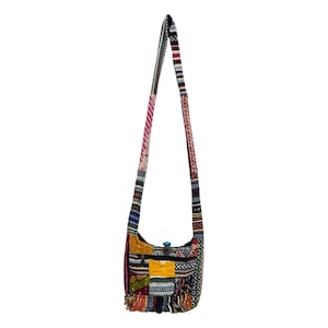 以下が含まれることがあります： 長いストラップが付いた、カラフルなパッチワークのショルダーバッグ。ピンク、青、黄色、赤など、さまざまな生地の柄と色があります。ジッパー付きのポケットと、底にフリンジが付いています。