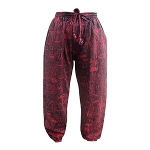 May include: Red trousers with a black and white print of abstract shapes. The trousers have an elastic waistband with a drawstring.