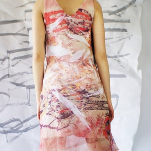 Puede incluir: Un vestido transparente sin mangas con estampado floral y geom&eacute;trico en tonos rosa, rojo, blanco y marr&oacute;n. El vestido tiene un escote en V y una silueta fluida.