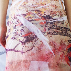 Puede incluir: Un vestido blanco transparente con estampado floral en tonos rosa, rojo y amarillo. El vestido tiene un aspecto fluido y et&eacute;reo, perfecto para una fiesta de verano o una ocasi&oacute;n especial.